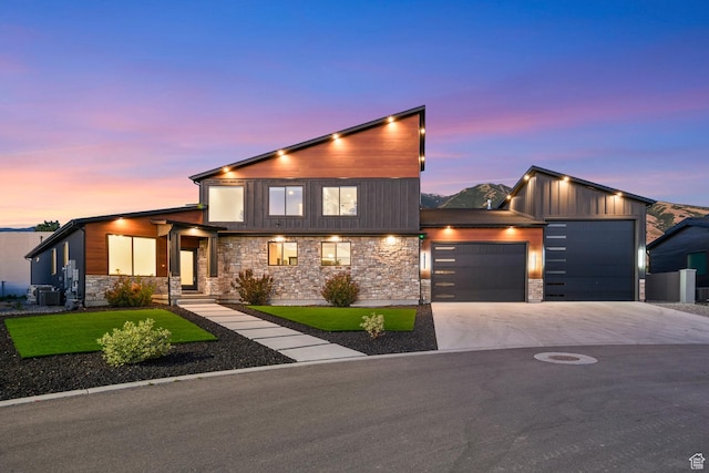 12719 S Outlaw Pl E, Draper, UT 84020 - contemporary house with an attached garage, concrete driveway, stone siding, central air condition unit, and a lawn