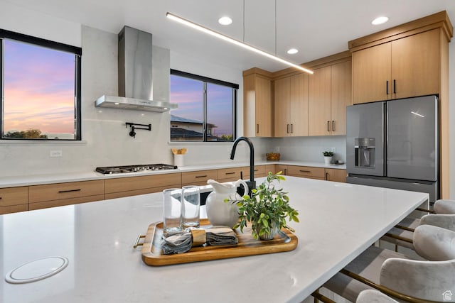 12719 S Outlaw Pl E, Draper, UT 84020 - kitchen with wall chimney range hood, appliances with stainless steel finishes, a kitchen bar, recessed lighting, and light brown cabinets