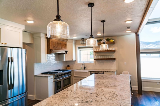 300 S 100th St W, Garden City, UT 84028 - kitchen with appliances with stainless steel finishes, backsplash, a textured ceiling, baseboards, and light stone counters
