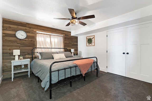 689 N Cambry Dr, Garden City, UT 84028 - bedroom featuring wood walls, dark carpet, baseboards, a closet, and ceiling fan