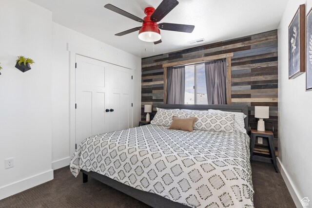 689 N Cambry Dr, Garden City, UT 84028 - bedroom with dark colored carpet, an accent wall, baseboards, wooden walls, and ceiling fan