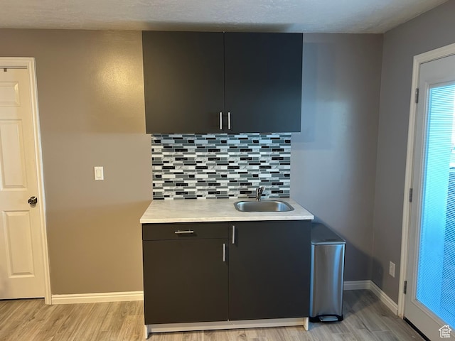 5029 W Copper Meadow Ln S, West Jordan, UT 84088 - kitchen with light wood-style flooring, decorative backsplash, light countertops, and dark cabinetry