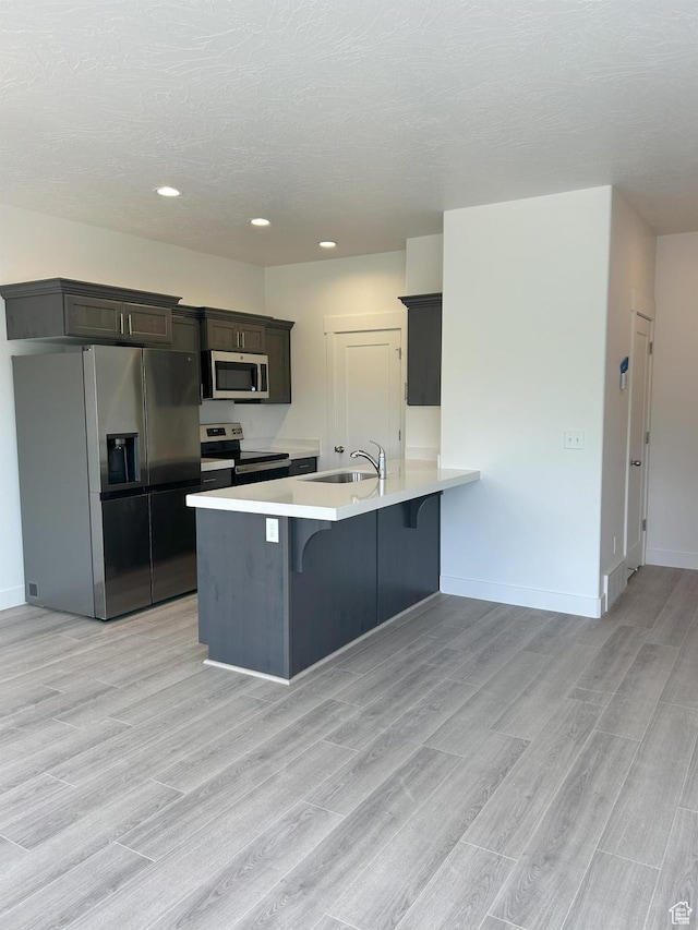5118 E Lakefield Dr N, Eagle Mountain, UT 84005 - kitchen with stainless steel appliances, a kitchen bar, light countertops, a sink, and a peninsula