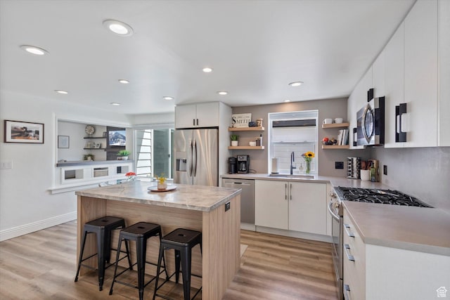 6571 S Jefferson St, Murray, UT 84107 - kitchen with appliances with stainless steel finishes, open shelves, a sink, a breakfast bar, and a kitchen island