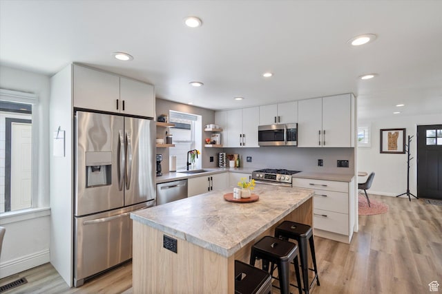 6571 S Jefferson St, Murray, UT 84107 - kitchen featuring stainless steel appliances, open shelves, light countertops, a sink, and light wood finished floors