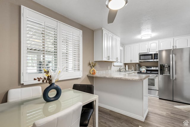 8265 S 3450 W, West Jordan, UT 84088 - kitchen with stainless steel appliances, light wood-style floors, white cabinetry, a peninsula, and a sink