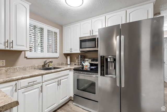 8265 S 3450 W, West Jordan, UT 84088 - kitchen featuring stainless steel appliances, light wood-type flooring, a sink, white cabinetry, and light countertops