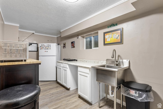 8265 S 3450 W, West Jordan, UT 84088 - kitchen featuring freestanding refrigerator, light wood-style floors, a textured ceiling, crown molding, and light countertops