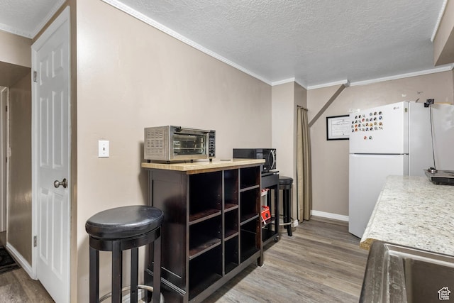 8265 S 3450 W, West Jordan, UT 84088 - kitchen with freestanding refrigerator, wood finished floors, ornamental molding, a textured ceiling, and baseboards