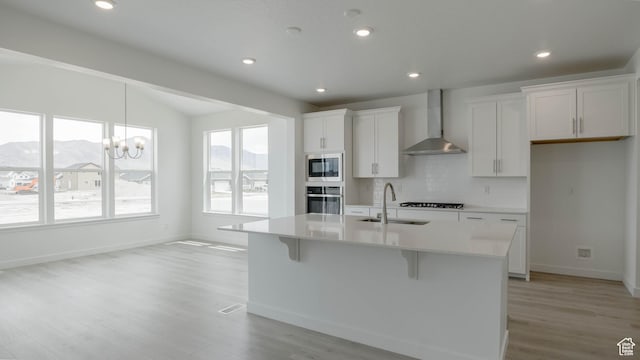 5502 N Trailside Unit 503, Eagle Mountain, UT 84005 - kitchen featuring wall chimney range hood, stainless steel appliances, a sink, a center island with sink, and backsplash