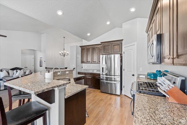 3352 N 200 W, Lehi, UT 84043 - kitchen featuring stainless steel appliances, a sink, vaulted ceiling, a kitchen bar, and a chandelier
