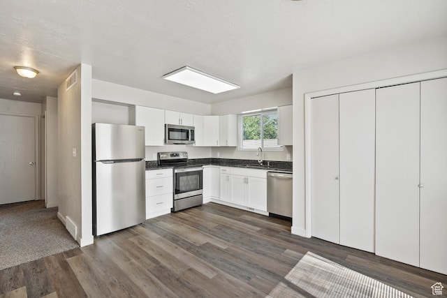 221 N Pingree Ave E, Ogden, UT 84404 - kitchen with stainless steel appliances, dark countertops, a sink, dark wood-type flooring, and white cabinetry