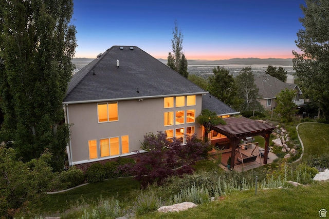 603 S Temple Hill Cir E, Bountiful, UT 84010 - back of house at dusk featuring stucco siding, a pergola, roof with shingles, and a patio