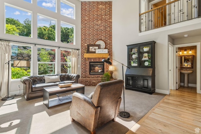 603 S Temple Hill Cir E, Bountiful, UT 84010 - living room featuring a towering ceiling, a brick fireplace, light wood finished floors, and baseboards