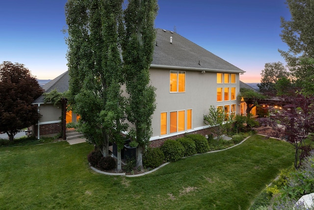 603 S Temple Hill Cir E, Bountiful, UT 84010 - back of house at dusk featuring stucco siding, a yard, and a shingled roof