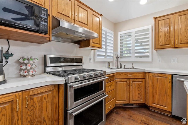 938 E Bernay Cir, Sandy, UT 84094 - kitchen featuring appliances with stainless steel finishes, under cabinet range hood, a sink, dark wood-style flooring, and brown cabinets