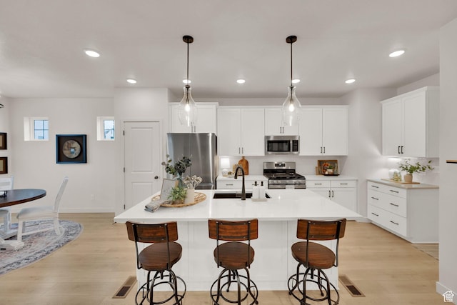 11693 S Watercourse Rd, South Jordan, UT 84009 - kitchen featuring appliances with stainless steel finishes, a sink, a breakfast bar, light wood-style floors, and recessed lighting