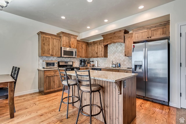 7259 S Viansa Ct, Midvale, UT 84047 - kitchen with stainless steel appliances, light wood-style flooring, a breakfast bar area, decorative backsplash, and recessed lighting