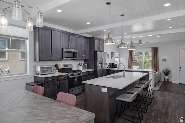 1097 W Wasatch Spring Rd, Kamas, UT 84036 - kitchen with stainless steel appliances, dark wood-style floors, an island with sink, a breakfast bar area, and light countertops