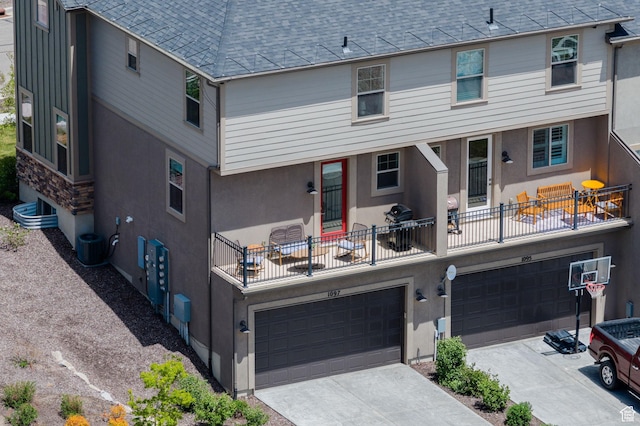 1097 W Wasatch Spring Rd, Kamas, UT 84036 - rear view of property featuring a garage, roof with shingles, concrete driveway, stucco siding, and cooling unit