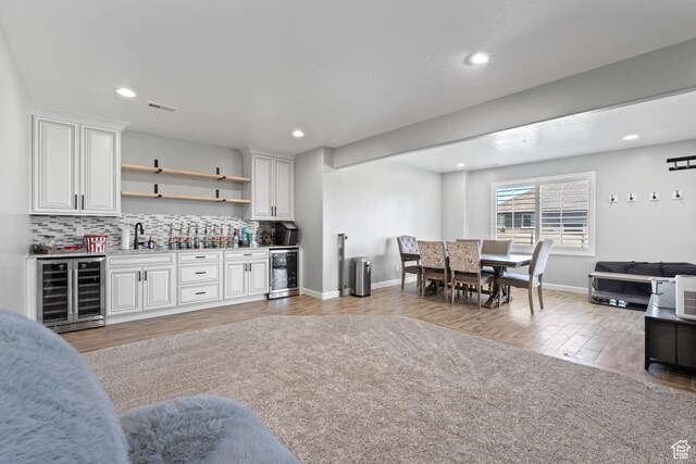 5284 W Orchard Spring Dr S, Herriman, UT 84096 - indoor wet bar with wine cooler, light wood-style flooring, decorative backsplash, recessed lighting, and baseboards