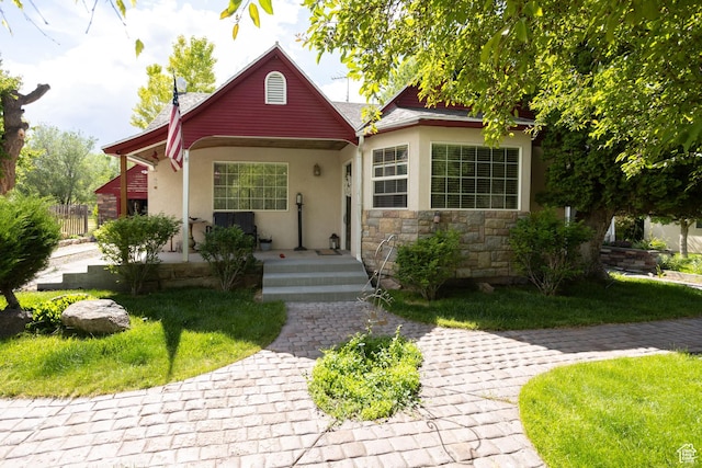 40 S Main St, Glenwood, UT 84730 - view of front facade featuring stucco siding, covered porch, stone siding, and a front lawn