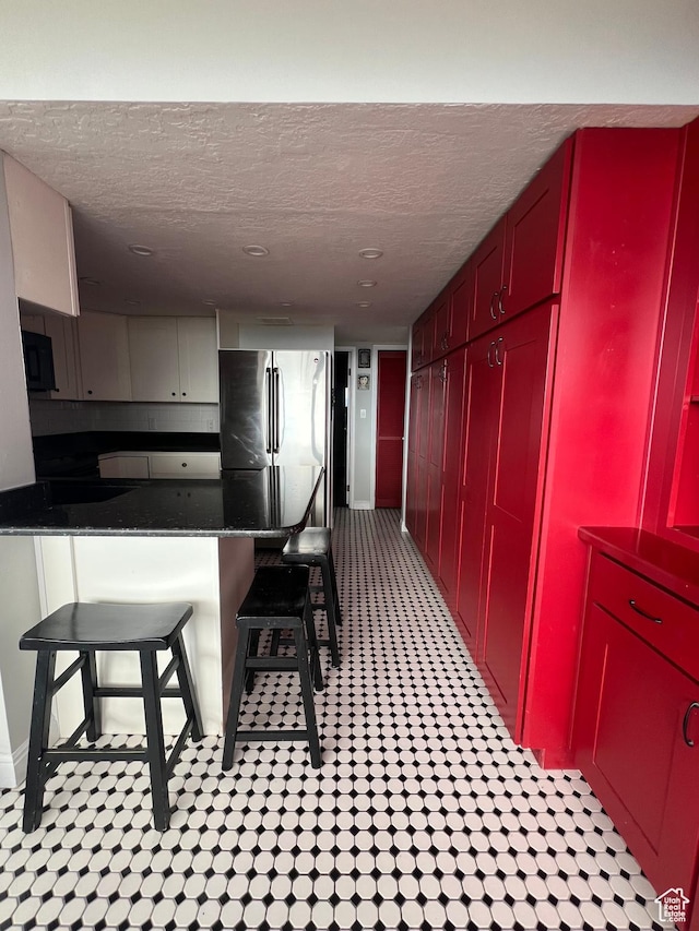241 N Vine St W Unit 808W, Salt Lake City, UT 84103 - kitchen with freestanding refrigerator, a textured ceiling, red cabinets, black microwave, and a kitchen breakfast bar