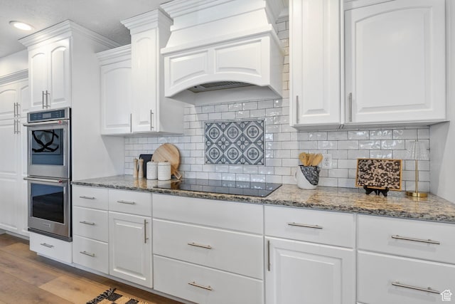 13226 S Cocomo Ct W, Herriman, UT 84096 - kitchen featuring premium range hood, stainless steel double oven, black electric cooktop, wood finished floors, and stone counters