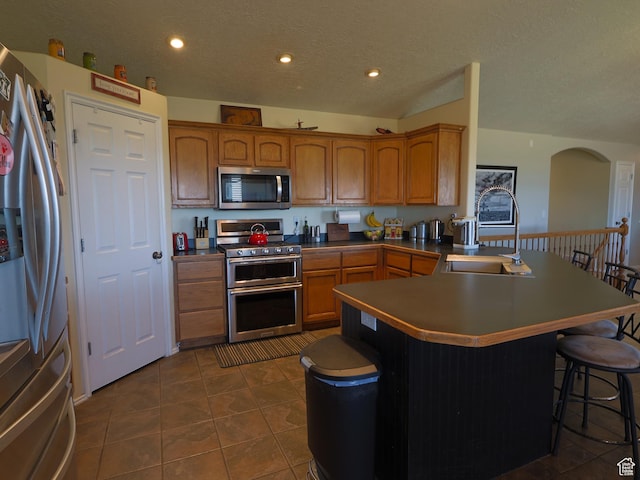 113 N 4950 W, West Point, UT 84015 - kitchen with appliances with stainless steel finishes, a sink, a breakfast bar area, a peninsula, and dark tile patterned flooring