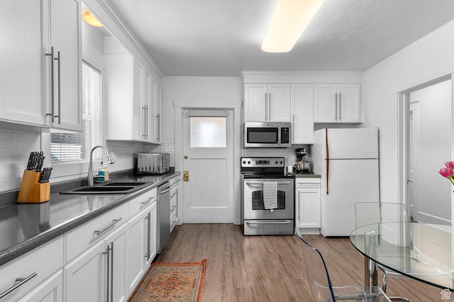 341 N 300 W, Provo, UT 84601 - kitchen with appliances with stainless steel finishes, a sink, wood finished floors, backsplash, and white cabinetry