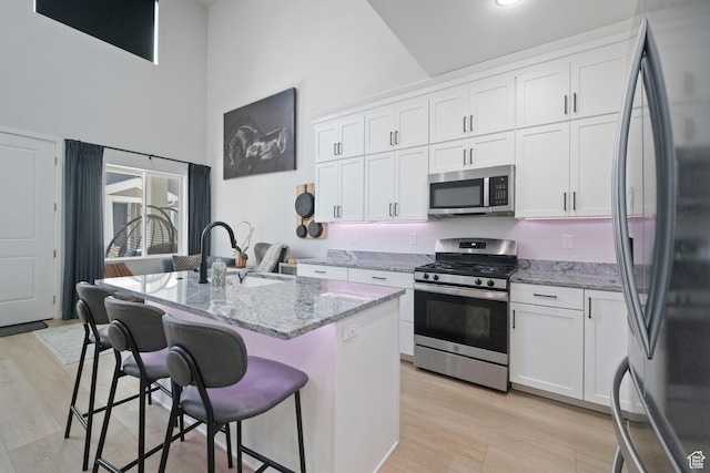 15002 S Wild Horse Way, Bluffdale, UT 84065 - kitchen with appliances with stainless steel finishes, a sink, high vaulted ceiling, light stone countertops, and a kitchen bar