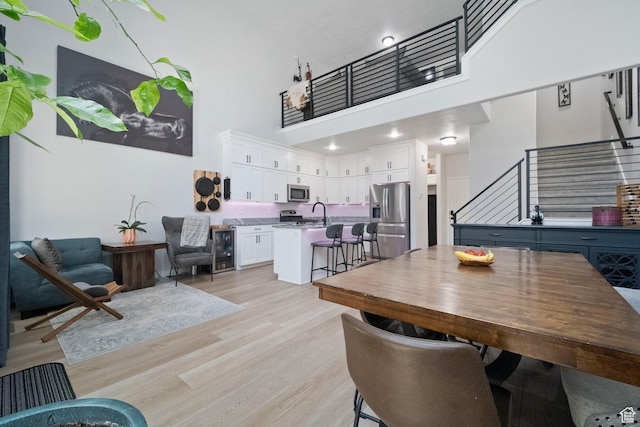 15002 S Wild Horse Way, Bluffdale, UT 84065 - dining area with a towering ceiling, stairway, light wood-style flooring, and beverage cooler