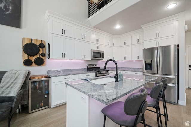 15002 S Wild Horse Way, Bluffdale, UT 84065 - kitchen with appliances with stainless steel finishes, wine cooler, light wood-type flooring, light stone countertops, and a sink