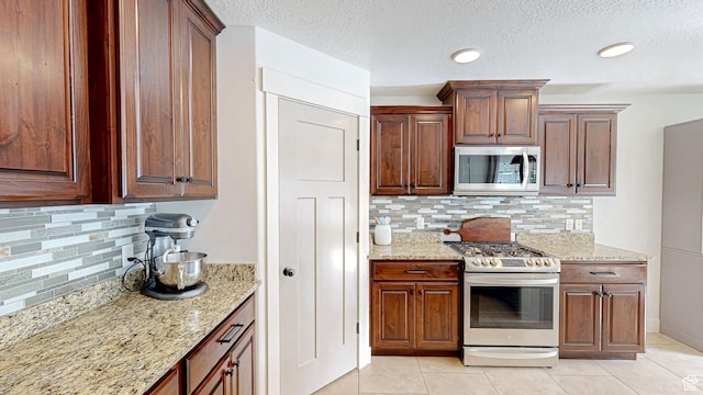 918 S River Ridge Lane, Spanish Fork, UT 84660 - kitchen with appliances with stainless steel finishes, decorative backsplash, light stone countertops, light tile patterned flooring, and a textured ceiling