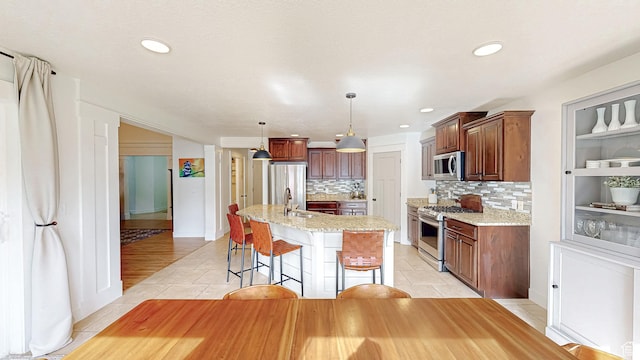918 S River Ridge Lane, Spanish Fork, UT 84660 - kitchen with appliances with stainless steel finishes, a sink, light tile patterned flooring, decorative backsplash, and an island with sink