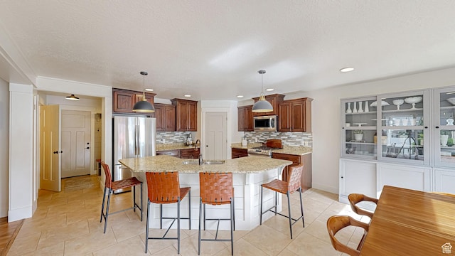 918 S River Ridge Lane, Spanish Fork, UT 84660 - kitchen with appliances with stainless steel finishes, a sink, tasteful backsplash, a kitchen island with sink, and a kitchen breakfast bar