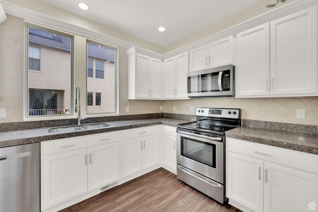 11379 S Oakmond Rd, South Jordan, UT 84009 - kitchen with stainless steel appliances, a sink, white cabinets, wood finished floors, and backsplash