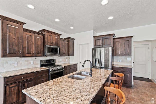449 Travertine Way, Santaquin, UT 84655 - kitchen with appliances with stainless steel finishes, a sink, dark brown cabinets, a center island with sink, and tasteful backsplash