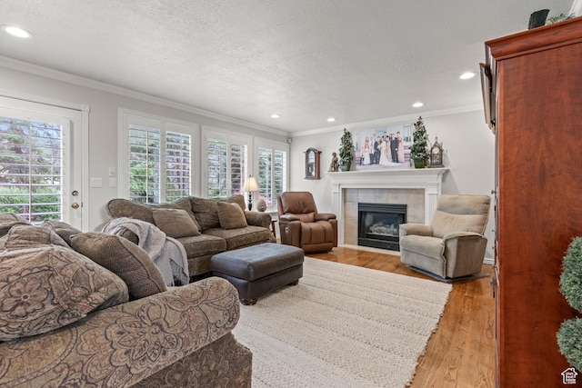 3330 N 175 W, North Ogden, UT 84414 - living room featuring ornamental molding, recessed lighting, a tiled fireplace, a textured ceiling, and light wood finished floors