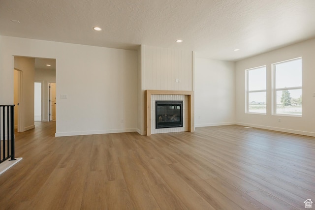 2597 E 360 S Unit 16, Spanish Fork, UT 84660 - unfurnished living room with light wood-style floors, a tile fireplace, recessed lighting, a textured ceiling, and baseboards