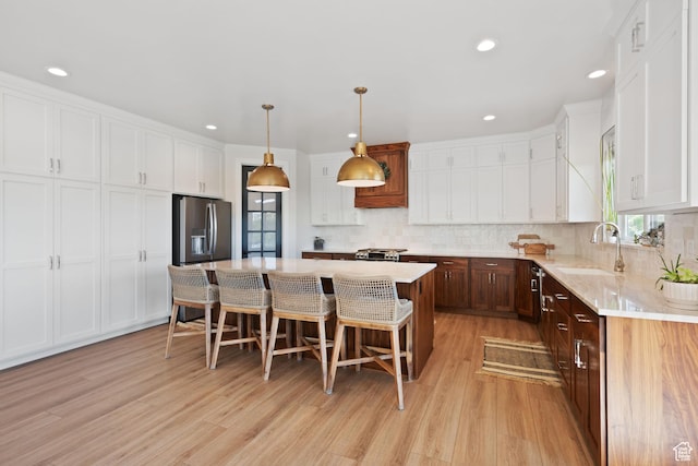 3812 S Mapleton Estates Dr, Mapleton, UT 84664 - kitchen featuring appliances with stainless steel finishes, a sink, light wood-style floors, white cabinetry, and a kitchen breakfast bar