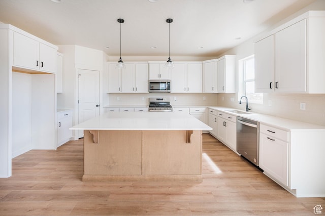 1089 E Blackfeet Dr Unit 518, Eagle Mountain, UT 84005 - kitchen with appliances with stainless steel finishes, a sink, a center island, light wood-style flooring, and a kitchen bar