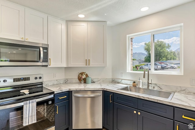 116 E Resaca Unit F3, Midvale, UT 84070 - kitchen with appliances with stainless steel finishes, a sink, white cabinetry, a textured ceiling, and recessed lighting