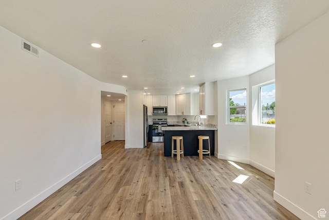 116 E Resaca Unit F3, Midvale, UT 84070 - kitchen with appliances with stainless steel finishes, a sink, baseboards, white cabinetry, and light wood-style flooring