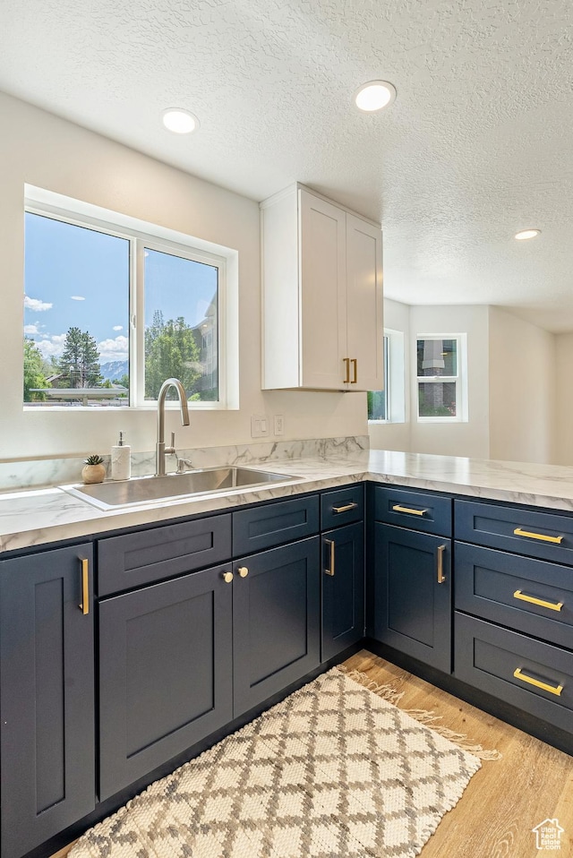 116 E Resaca Unit F3, Midvale, UT 84070 - kitchen with a sink, white cabinets, light wood-type flooring, light countertops, and a textured ceiling