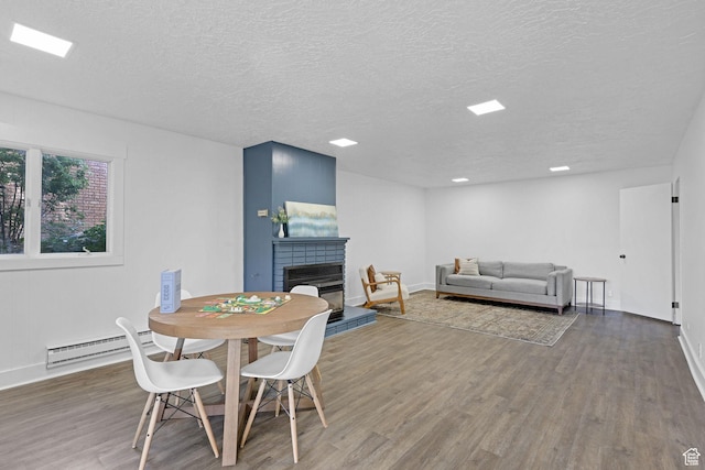 1507 Hudson St, Ogden, UT 84404 - dining space featuring wood finished floors, baseboard heating, a textured ceiling, baseboards, and a fireplace