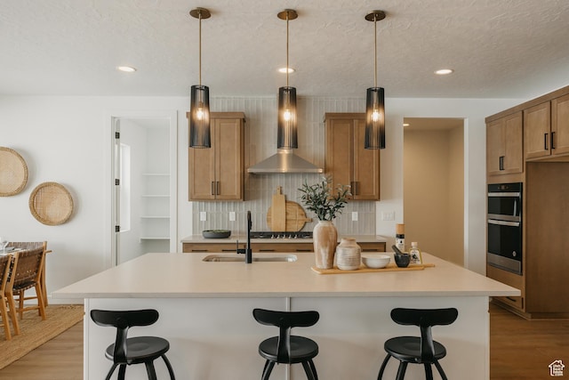 3537 E 1120 S Unit 110, Spanish Fork, UT 84660 - kitchen featuring wall chimney range hood, a sink, light wood-type flooring, backsplash, and recessed lighting