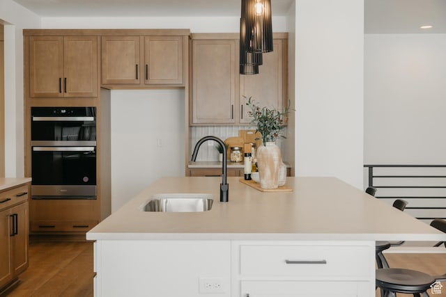 3537 E 1120 S Unit 110, Spanish Fork, UT 84660 - kitchen featuring stainless steel double oven, a sink, light countertops, a breakfast bar area, and dark wood finished floors