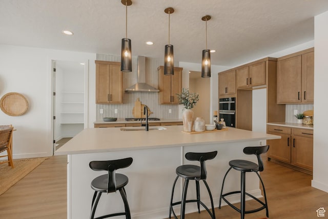 3537 E 1120 S Unit 110, Spanish Fork, UT 84660 - kitchen featuring wall chimney range hood, multiple ovens, tasteful backsplash, a sink, and light countertops