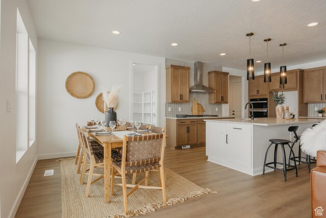 3537 E 1120 S Unit 110, Spanish Fork, UT 84660 - kitchen with wall chimney range hood, decorative backsplash, light wood-style flooring, stainless steel appliances, and recessed lighting